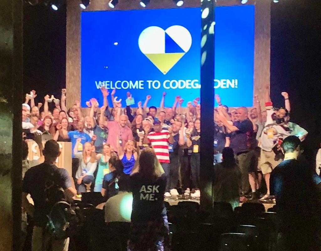 An image of a group of Umbraco Codegarden attendees gathered on a stage. They have their hands raised, waving, and there is a sign behind them saying "Welcome to Codegarden".
