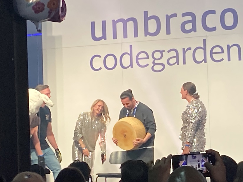 Man winning a giant cheese wheel on the Umbraco Codegarden stage