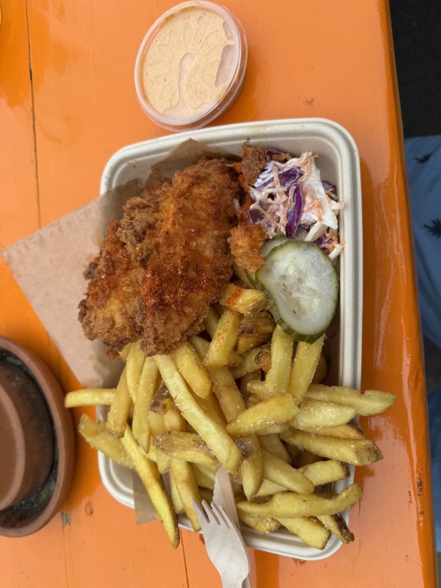 French fries, fried chicken, cucumber, coleslaw and dipping sauce in a carboard tray