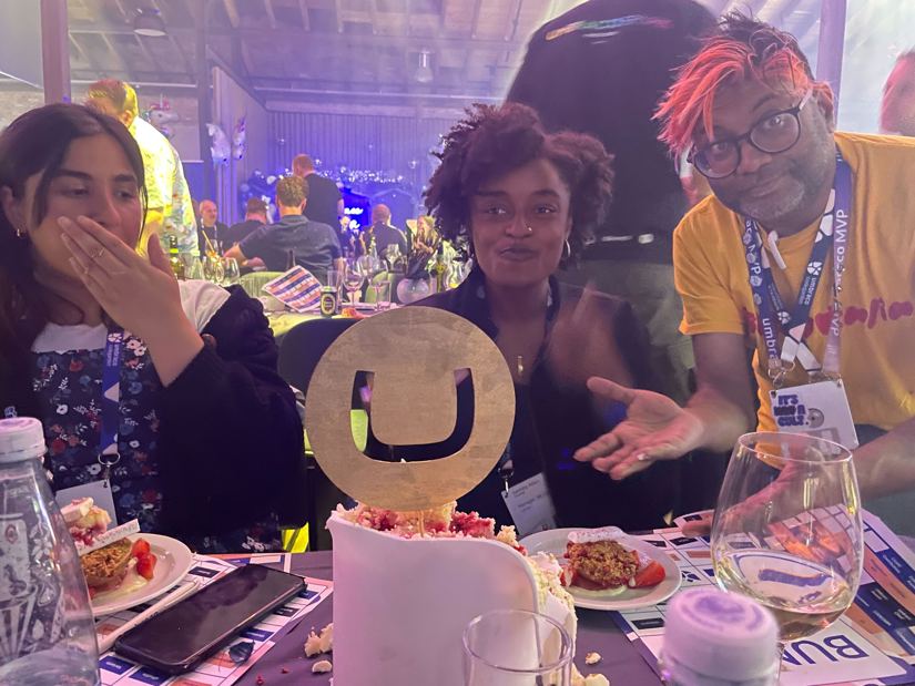 Three attendees with a the top part of a wedding cake and the Umbraco logo planted on top